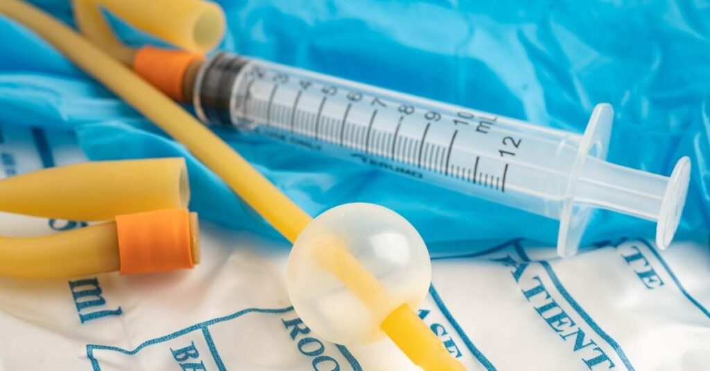 Foley catheter tube and medical syringe used for foley catheter care at home placed on sterile medical supplies.