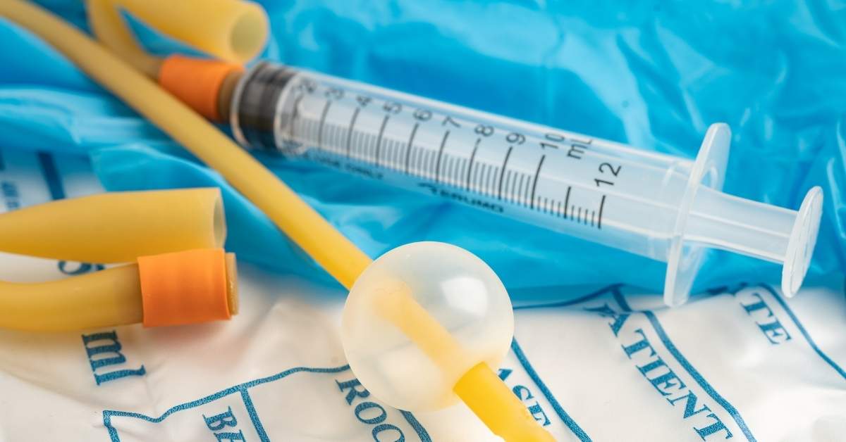 Foley catheter tube and medical syringe used for foley catheter care at home placed on sterile medical supplies.