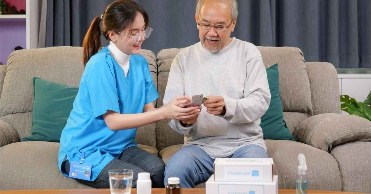 Home health caregiver helping an elderly man organize medications during a home visit, demonstrating supportive diabetes and cardiac management at home.
