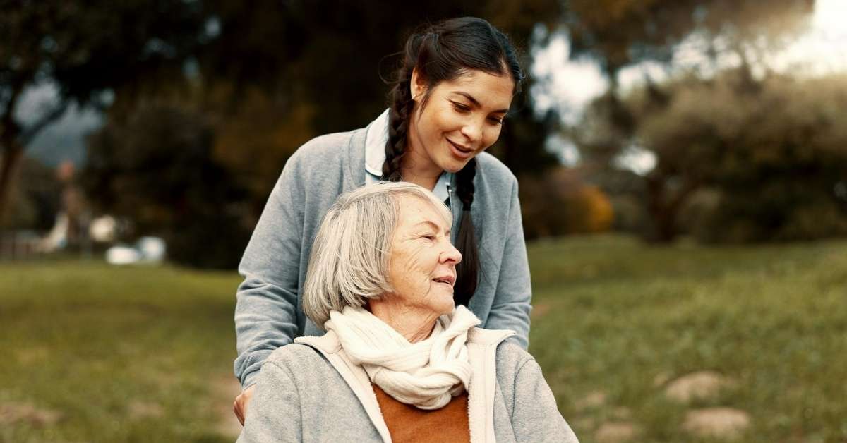 Compassionate home caregiver supporting an elderly woman outdoors, showing empathy and emotional care that improves patient recovery and well-being.